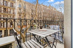 uma mesa de madeira e banco numa varanda com edifícios em Flateli Borrell em Barcelona