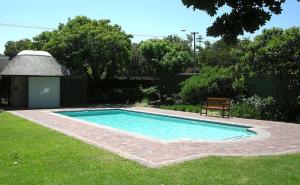 a swimming pool with a bench in a yard at Constantia Cottage in Cape Town