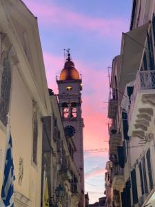 Un edificio con una torre dell'orologio in mezzo a una strada di Aristotelous Chris Studio a Città di Corfù