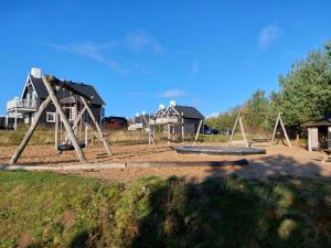 um parque infantil vazio num quintal com casas ao fundo em Beautiful Holiday Home With Spa And Sauna Close To Nature em Gjern