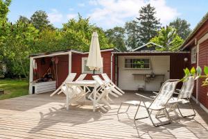 einen Tisch und Stühle auf einer Terrasse mit einem Sonnenschirm in der Unterkunft Lovely Holiday Home Near The Beach in Vordingborg