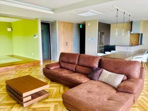 uma sala de estar com um sofá de couro castanho e uma mesa em CONDOMINIUM 紅-BIN- em Okinawa City