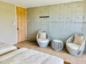 a bedroom with two wicker chairs and a bed at CONDOMINIUM 紅-BIN- in Okinawa City