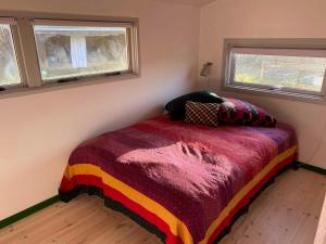 霍爾拜克的住宿－Family Friendly Holiday Home In Or，一间卧室配有一张带彩色毯子的床和两个窗户