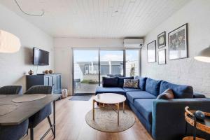 Una sala de estar con un sofá azul y una mesa. en Holiday Home In The First Row To The North Sea, en Vestervig
