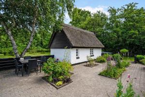 a small house with a thatched roof in a garden at Older Thatched Farmhouse, Approx, 400 Meters From The Water in Ørsted