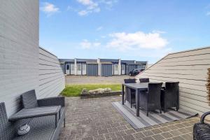 un patio con mesa, sillas y un perro en Holiday Home In The First Row To The North Sea, en Vestervig