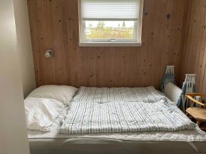 ein unmaskiertes Bett in einem Zimmer mit Fenster in der Unterkunft Holiday Home With Sauna And View To The Baltic Sea in Nordborg
