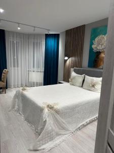 a bedroom with a white bed and blue curtains at Квартира по вул. Огієнка 2а in Lutsk