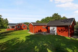 eine rote Scheune und ein rotes Haus im Hof in der Unterkunft Bright, Spacious And Cozy Cottage, 200 M From The Beach in Hadsund