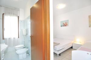 a white bathroom with a toilet and a sink at Casette Baradel - Agenzia Caorle in Caorle +33 photos