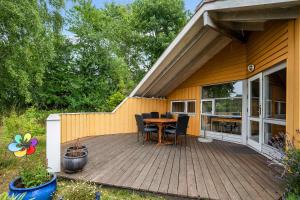 een houten terras met een tafel en stoelen op een huis bij Welcome To Our Lovely Holiday Home in Gilleleje