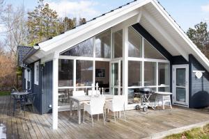 een afgeschermde veranda met een tafel en stoelen op een terras bij Newer Holiday Home In Green Surroundings in Jægerspris