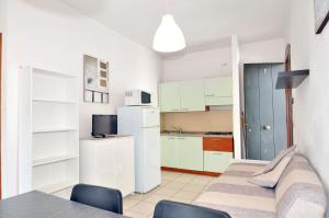 - une cuisine avec des placards blancs, une table et des chaises dans l'établissement Casette Baradel - Agenzia Caorle, à Caorle