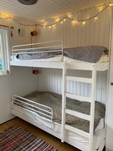 Ce lit se trouve dans un dortoir doté de 2 lits superposés blancs et d'une fenêtre. dans l'établissement Peaceful, Idyllic Summerhouse, - Beach And Nature Sanctuary, à Spottrup