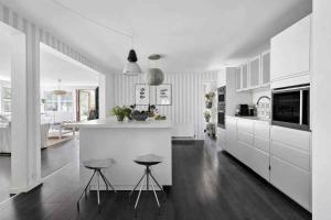 een witte keuken met 2 krukken en een aanrecht bij Luxurious Holiday Home In Tisvildeleje in Tisvildeleje