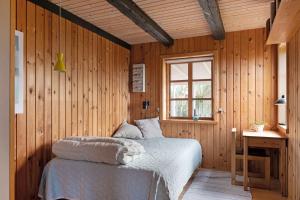 een slaapkamer met een bed in een houten muur bij Wooden House With A View Of The North Sea in Lemvig