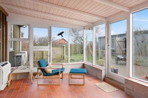een afgeschermde veranda met twee stoelen en een vliegende vogel bij Wooden House With A View Of The North Sea in Lemvig