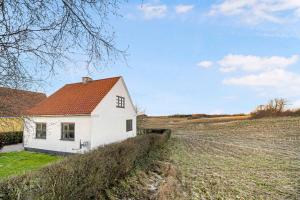 uma casa branca no meio de um campo em A Lovely Holiday Home In Quiet, Scenic Surroundings em Rønne