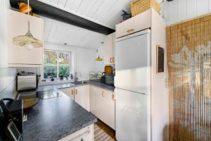 a kitchen with white cabinets and a white refrigerator at Cozy Holiday Home Close To Forest And Beach in Hasle
