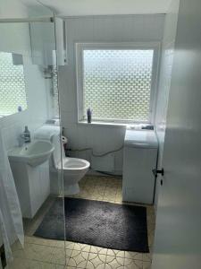 La salle de bains est pourvue de toilettes, d'un lavabo et d'une fenêtre. dans l'établissement Quietly Located Holiday Home Close To The Sea, à Brenderup