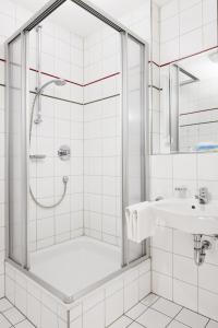 baño blanco con ducha y lavamanos en Hotel Pfaubräu, en Trostberg an der Alz
