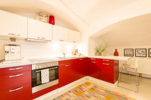 a kitchen with red cabinets and a white counter at Sound of Music World Appartement in Salzburg