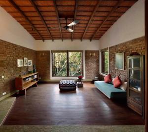 uma sala de estar com um sofá azul e paredes de tijolos em ama Stays & Trails The Mango House, Alibag em Alibag