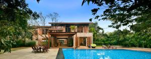 uma casa com piscina em frente a uma casa em ama Stays & Trails The Mango House, Alibag em Alibag