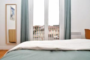 um quarto com uma cama e uma grande janela em Vue Pyrénéenne Élégante avec 2 chambres em Tarbes