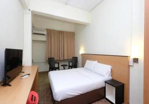 a bedroom with a bed and a desk and a television at Hotel 75 Temerloh in Temerloh