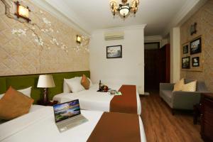 een hotelkamer met 2 bedden en een bank bij Golden Lotus Hotel & Spa in Hanoi