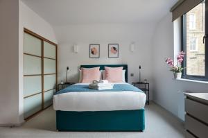 a bedroom with a blue bed with pink pillows at Hammersmith Mews by Viridian Apartments in London