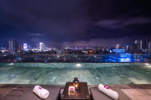 a rooftop swimming pool with a city skyline at night at San Marino Boutique Danang - 10 mins to Dragon Bridge & 15 mins to My Khe Beach in Da Nang