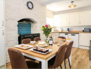 eine Küche mit einem Holztisch und Stühlen drumherum in der Unterkunft Babbling Brook Cottage in Stony Middleton