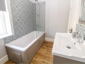 La salle de bains est pourvue d'une baignoire, d'un lavabo et d'une douche. dans l'établissement Babbling Brook Cottage, à Stony Middleton