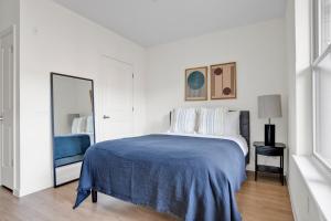 Un dormitorio blanco con una cama y un espejo. en Studio w WD Gym Rooftop Steps from T stop BOS-534, en Somerville
