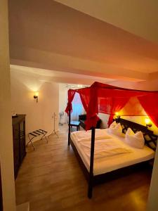 Hotel zur Römerbrücke في نيوفيد: غرفة نوم مع سرير بمظلة حمراء