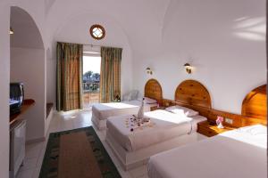 a hotel room with two beds and a clock on the wall at Pensee Royal Garden Beach Resort in Quseir