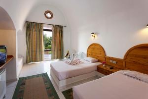 a bedroom with two beds and a tv and a window at Pensee Royal Garden Beach Resort in Quseir