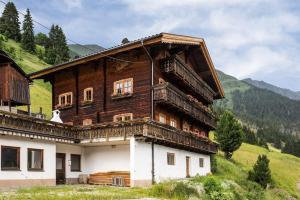 een groot houten huis met een balkon op een heuvel bij Haus Oschtna in Sankt Veit in Defereggen