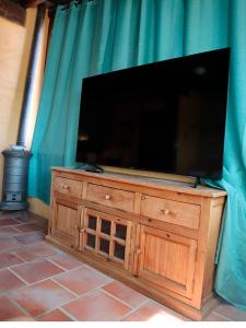 TV de pantalla plana grande en la parte superior de una cómoda de madera en Casa Rural EL TRULL, en Canet lo Roig