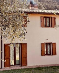een wit huis met houten deuren en een boom bij Agriturismo Il Sorbo Appartamento Menta in Sticciano