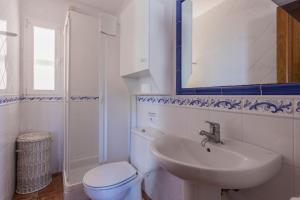 W łazience znajduje się toaleta, umywalka i lustro. w obiekcie Villa S'illot 105 By MENORCARENTALS w Son Bou +15 zdjęć