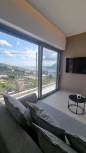 1 dormitorio con ventana grande, sofá y TV en Marigold Apartments en La Canea