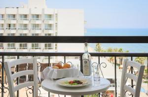 a table with a bottle of wine and a plate of food at Sandy Beach Hotel & Spa - ex Sentido in Larnaca