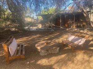 2 chaises et une table en face d'une cabine dans l'établissement El Huarango Eco retreat, à La Huaica