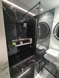 a black marble bathroom with a sink and a mirror at Grey Luxury Apartment in Gjirokastër