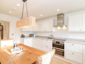 a kitchen with a wooden table and white cabinets at Stone Croft House in Chathill