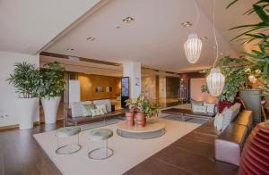 a living room with potted plants and a lobby at Occidental Faro in Faro